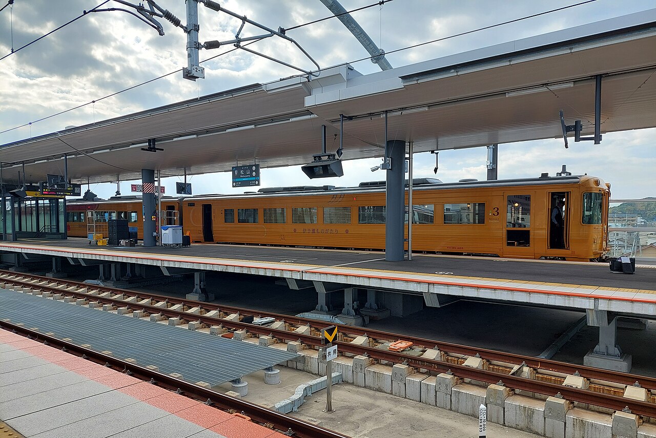 Gold Iyonada Monogatari carriages beside a platform at Matsuyama station