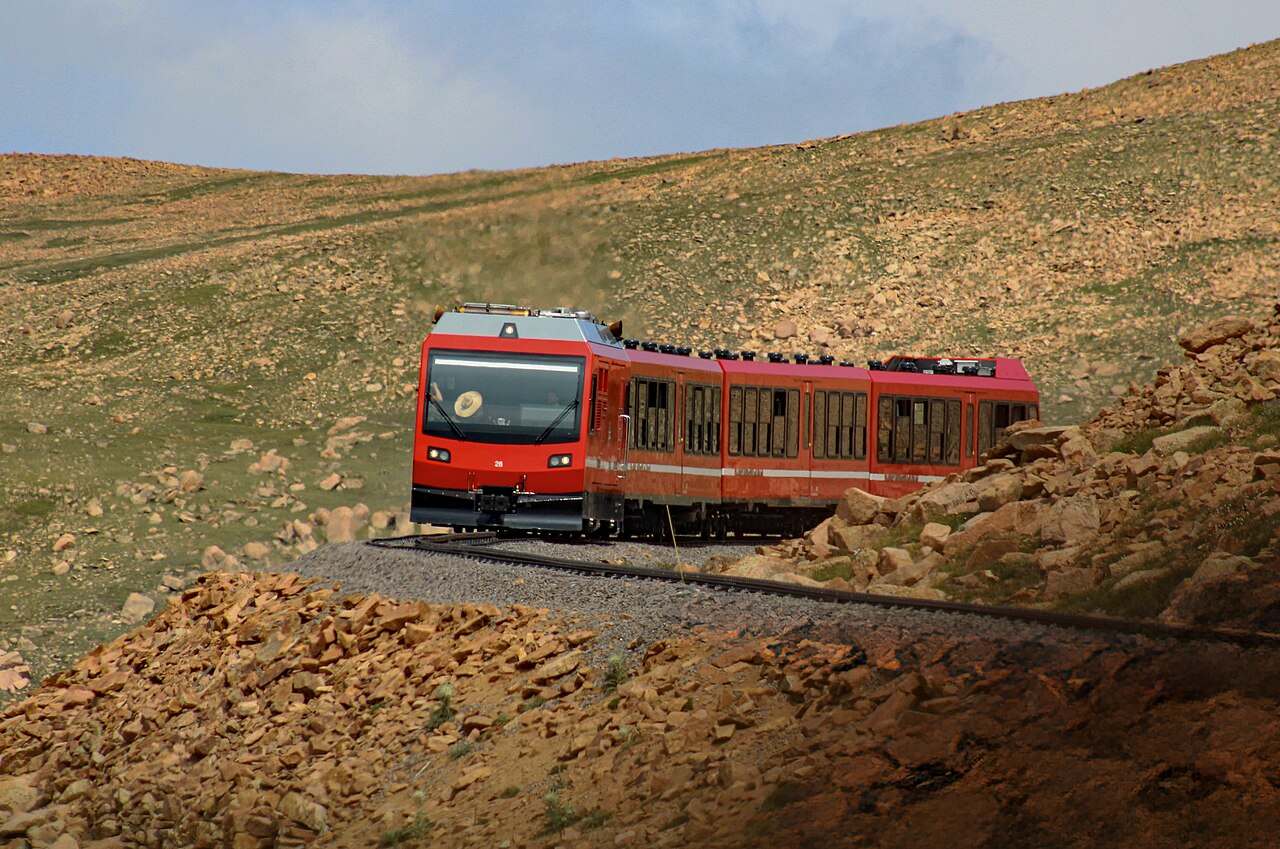 Red Pikes Peak cog train traveling through rocky mountain terrain near the summit